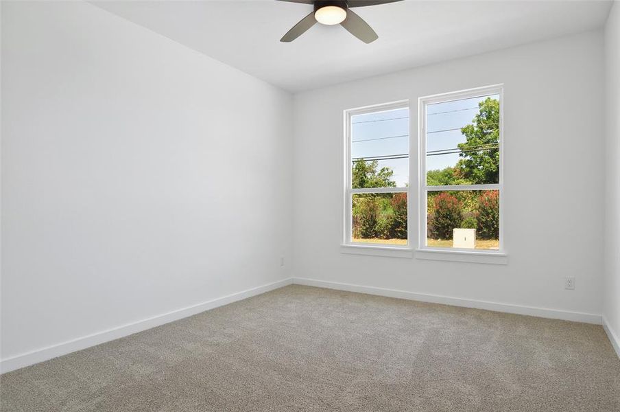 Carpeted empty room featuring ceiling fan and plenty of natural light
