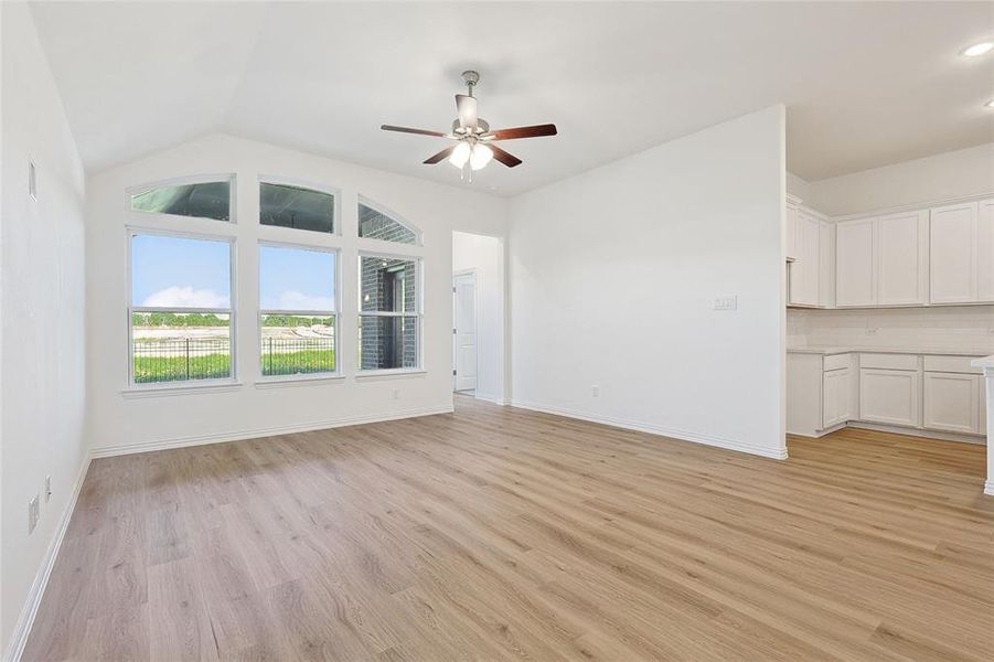 Unfurnished living room featuring light wood-type flooring, vaulted ceiling, and ceiling fan