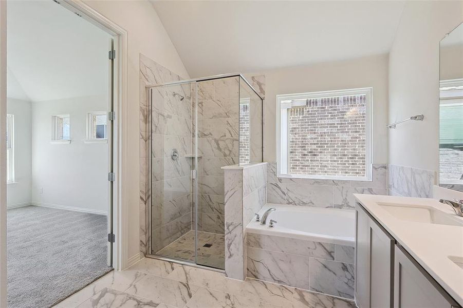 Bathroom with lofted ceiling, shower with separate bathtub, and vanity