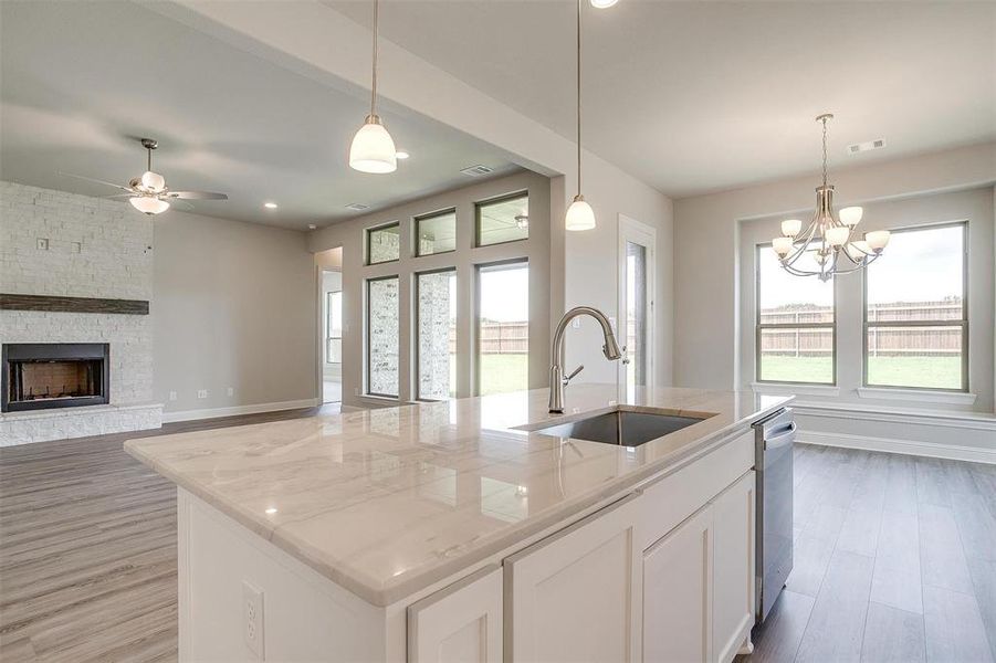 Kitchen with sink, light hardwood / wood-style flooring, and a kitchen island with sink