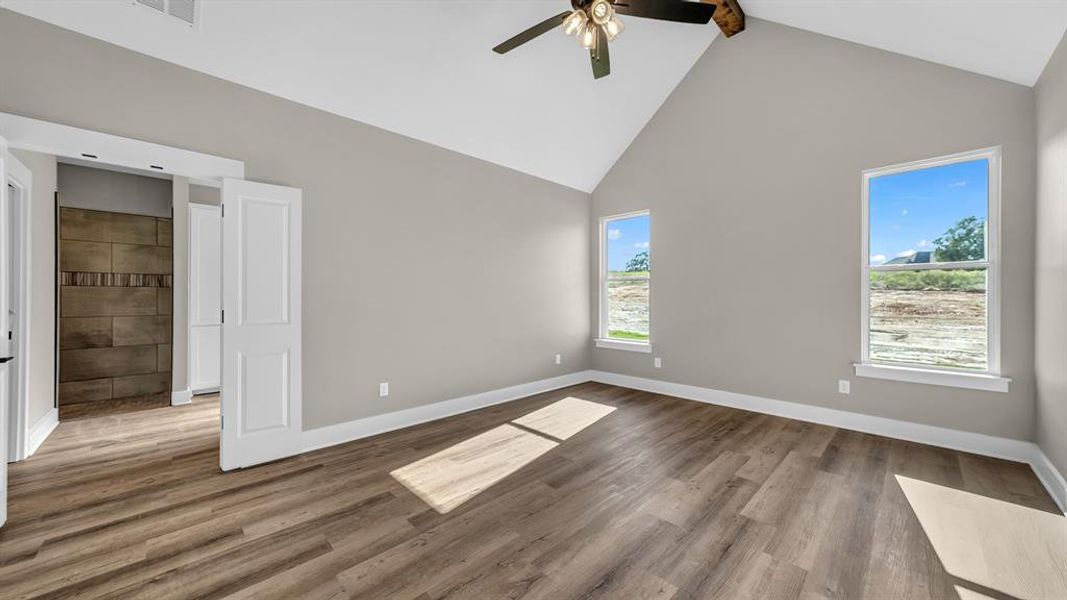 Primary bedroom featuring ceiling fan, beamed ceiling, and high vaulted ceiling