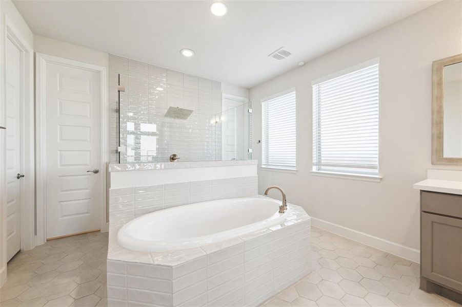 The primary bath includes a soaker tub located in the center of the bathroom with oversize shower behind.