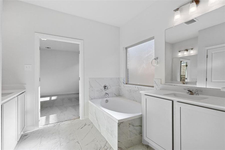 Bathroom featuring tile floors, tiled bath, and vanity