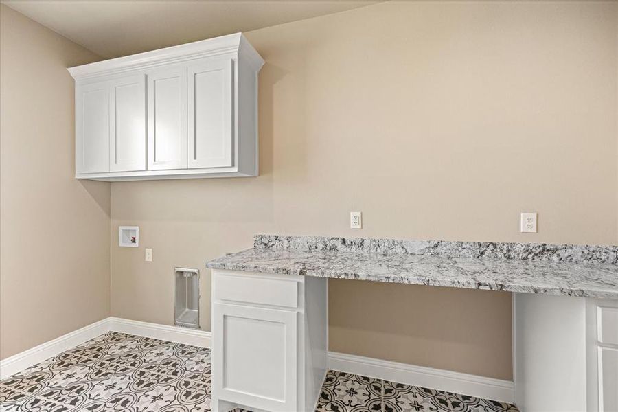 Clothes washing area featuring washer hookup, light tile patterned floors, and cabinets