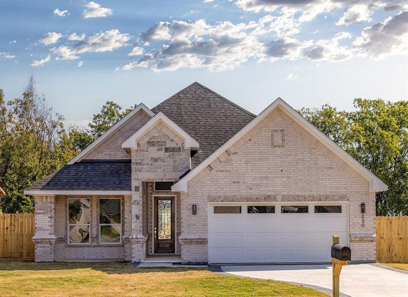 View of front facade featuring a front yard and a garage