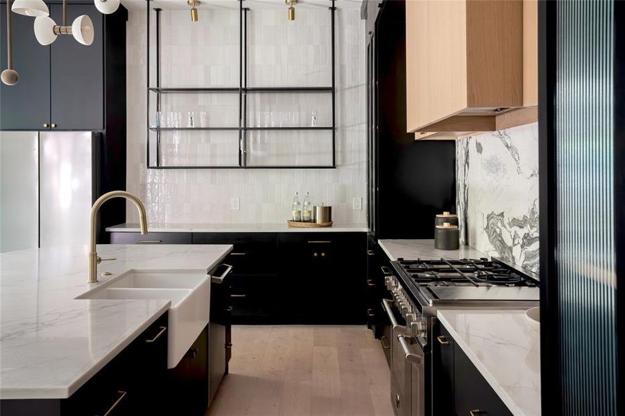 Kitchen with decorative light fixtures, light hardwood / wood-style flooring, backsplash, and stainless steel appliances