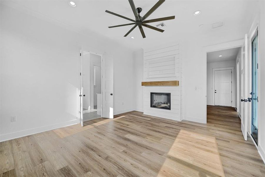 Unfurnished living room with ceiling fan, light hardwood / wood-style flooring, and a large fireplace