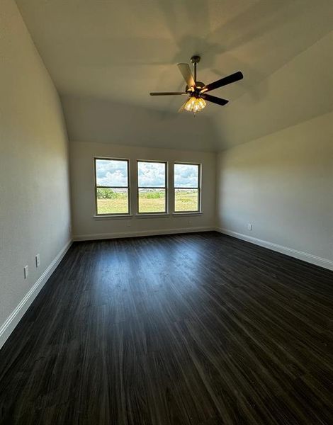 Spare room featuring lofted ceiling, dark hardwood / wood-style flooring, and ceiling fan