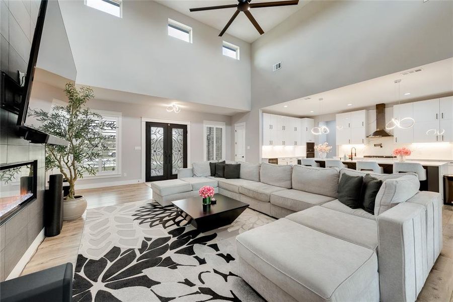 Living room featuring a towering ceiling, light hardwood / wood-style floors, ceiling fan, and sink