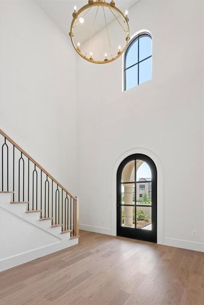 Foyer entrance with a towering ceiling, hardwood / wood-style floors, and a chandelier