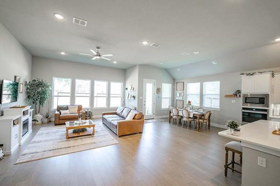 Living room with light wood-type flooring, lofted ceiling, ceiling fan, and a wealth of natural light