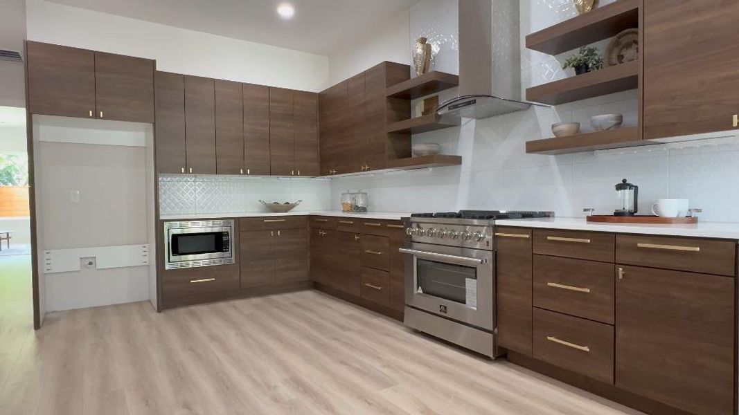 Kitchen featuring dark brown cabinetry, appliances with stainless steel finishes, light hardwood / wood-style flooring, and tasteful backsplash