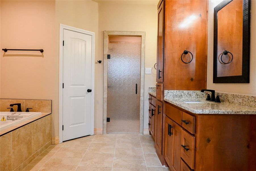 Primary bathroom has DUAL closets, granite countertops, shower with rainglass door and custom real wood cabinets.