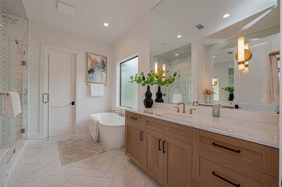Primary Bathroom features a freestanding tub as well as separate his & hers marble countertops