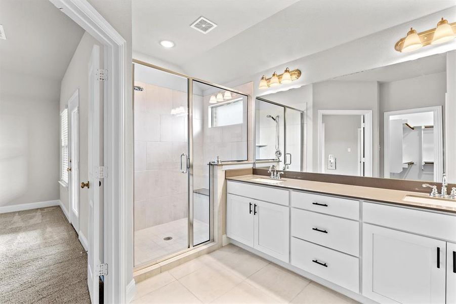 Bathroom with tile patterned floors, a shower with shower door, and vanity