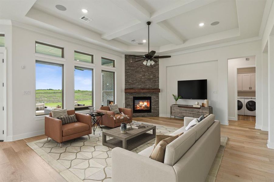 Living room featuring coffered ceiling, washer and clothes dryer, a stone fireplace, ceiling fan, and light wood-type flooring *VIRTUAL STAGING