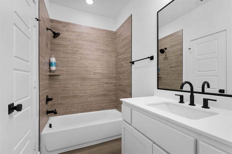 Bathroom featuring wood-type flooring, vanity, and tiled shower / bath combo