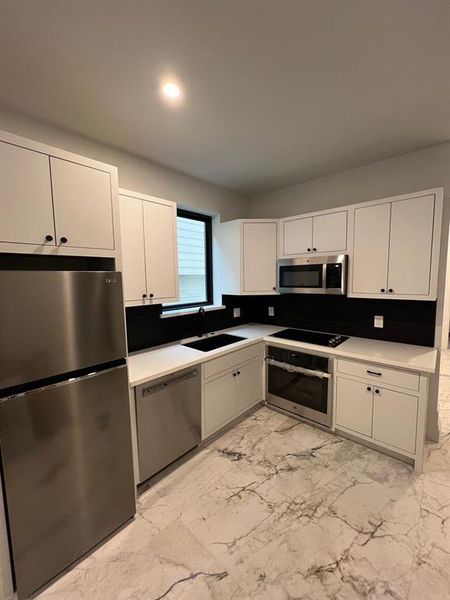 This photo showcases a modern and stylish unit with a full kitchen, complete with stainless steel appliances, ample counter space, and sleek cabinetry.