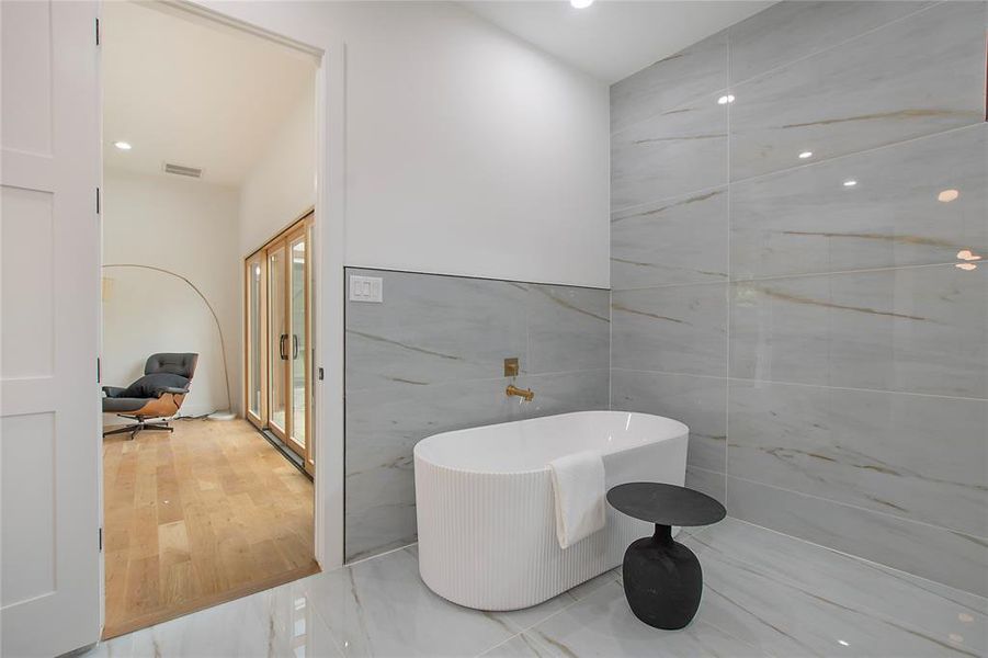 Bathroom featuring tile walls, a bathing tub, and hardwood / wood-style floors