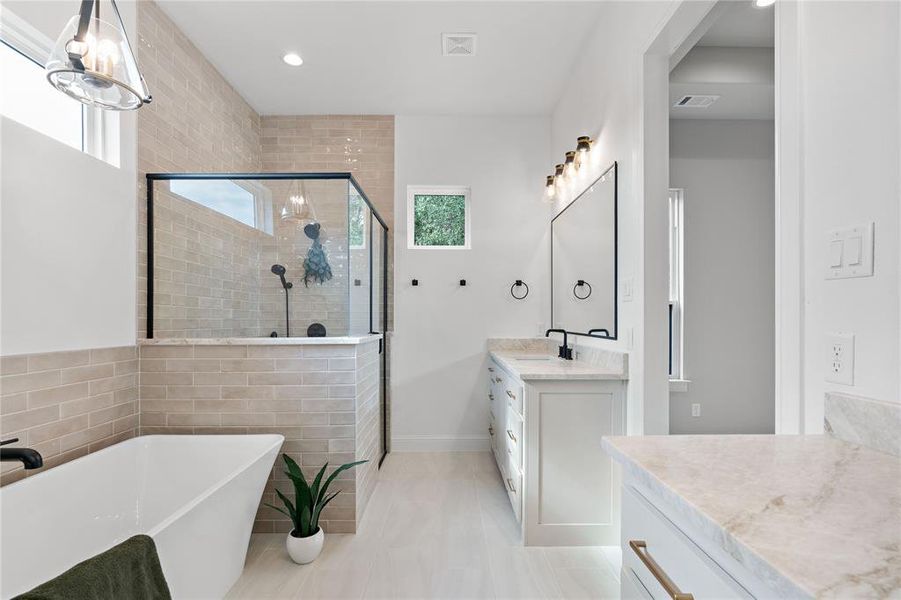 Bathroom with tile patterned floors, independent shower and bath, an inviting chandelier, tile walls, and vanity