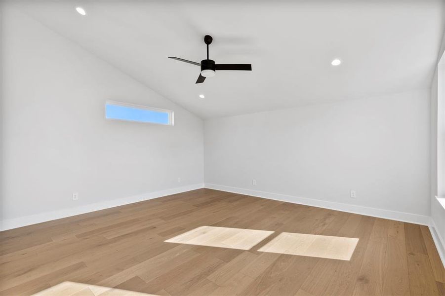 Empty room featuring ceiling fan, lofted ceiling, and light hardwood / wood-style flooring