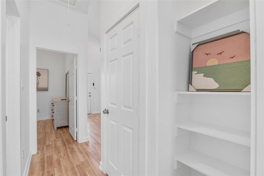 This photo shows a bright, hallway  and crisp white walls, and a  built-in shelving unit and easy access to adjacent rooms, enhancing the feeling of space and flow within the home.