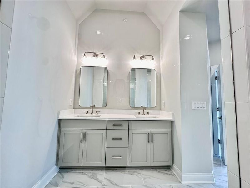 Gray cabinetry trails to the owners bathroom with vaulted ceilings