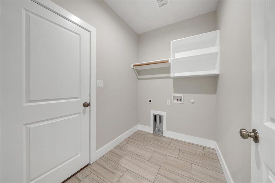 Clothes washing area with hookup for an electric dryer, gas dryer hookup, hookup for a washing machine, and light tile patterned floors