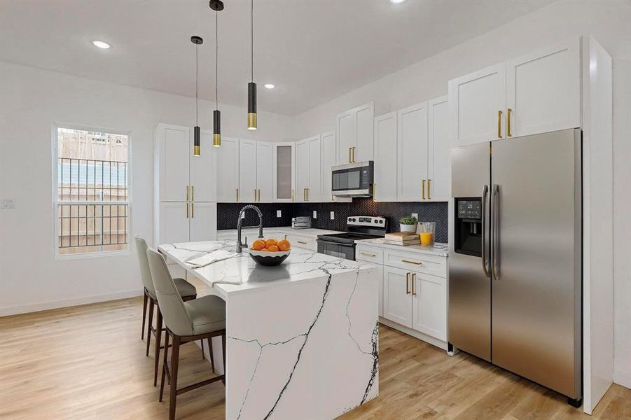 Kitchen with a center island with sink, light hardwood / wood-style floors, light stone countertops, and stainless steel appliances