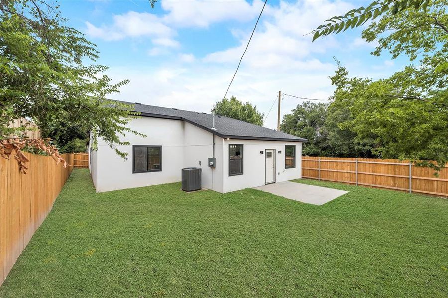 Back of property featuring a lawn, a patio, and cooling unit