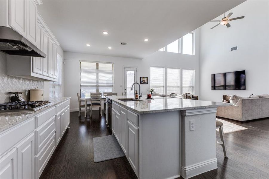 Kitchen with a granite counters, white cabinets and island with sink