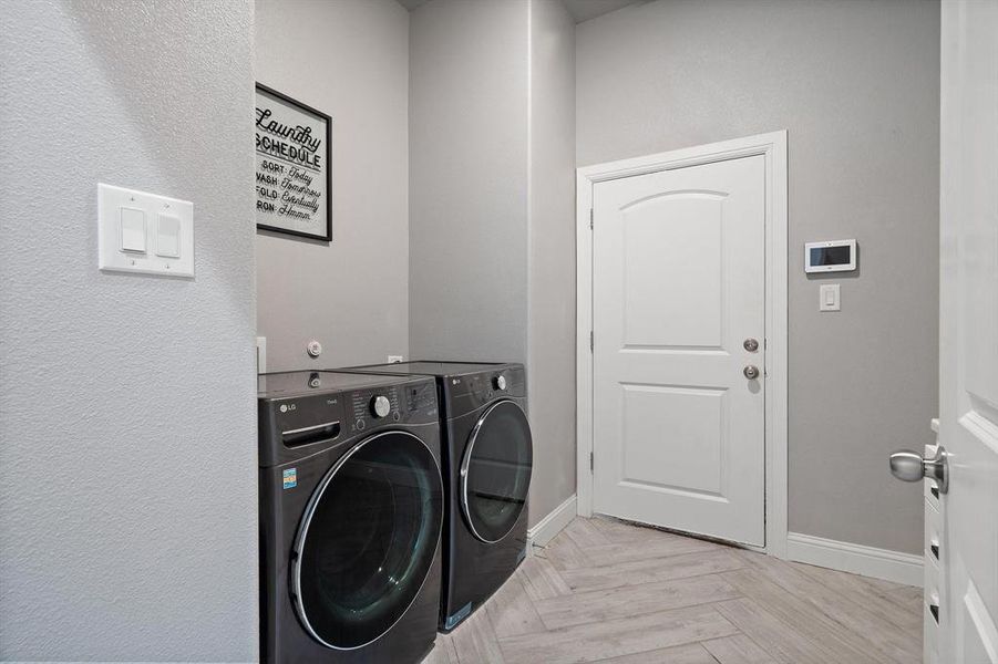 Laundry room featuring light parquet flooring and washing machine and clothes dryer