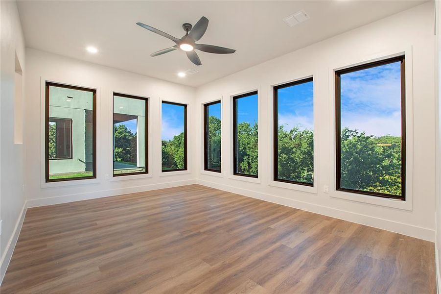 Empty room featuring hardwood / wood-style floors, a wealth of natural light, and ceiling fan