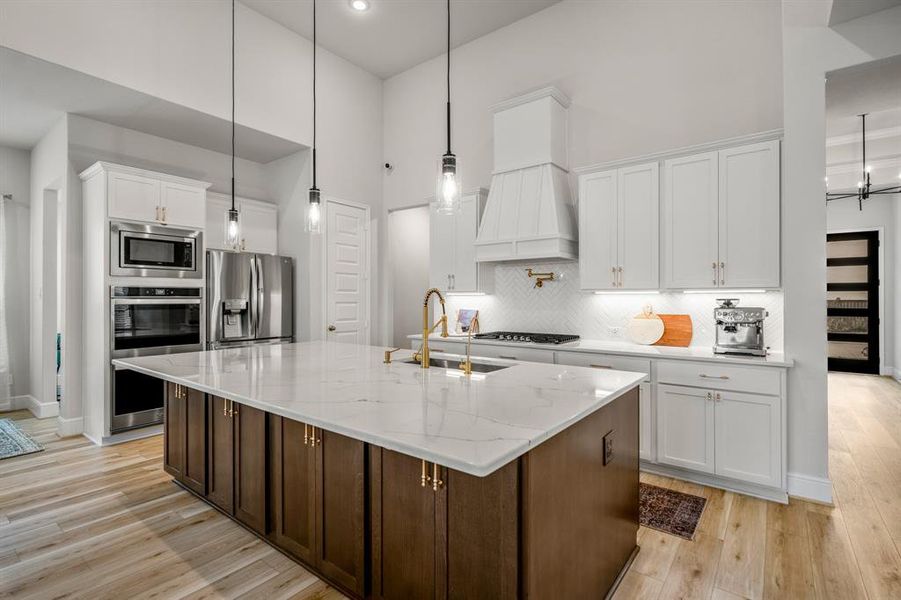 The kitchen boasts a deco wood paneled island with extra cabinets for storage at the front! Upgraded with built-in stainless steel appliances, a 5 burner gas cooktop, double ovens, and sleek white cabinets, this kitchen is ideal for cooking for the whole family or hosting holidays!