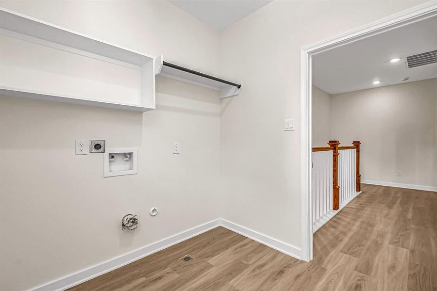 Laundry room is bright and features hanging rod and storage shelves.