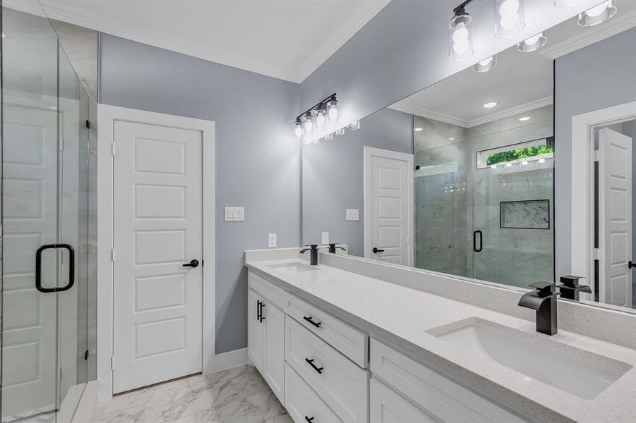 Bathroom featuring double vanity, ornamental molding, tile floors, and a shower with door