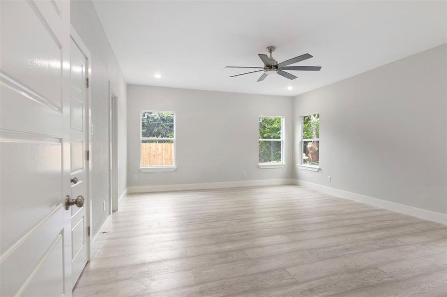 Empty room featuring a wealth of natural light, ceiling fan, and light wood-type flooring