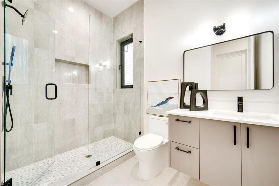 Bathroom with vanity, toilet, tile patterned flooring, and a shower with door