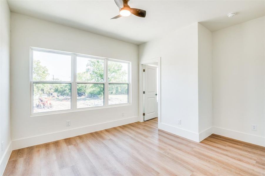 Empty room featuring ceiling fan, light wood-type flooring, and a wealth of natural light