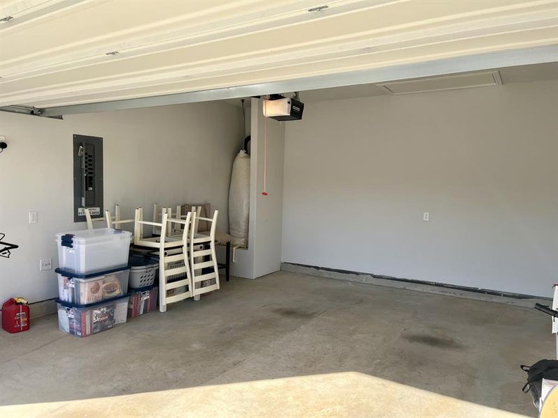 Garage featuring electric panel and a garage door opener