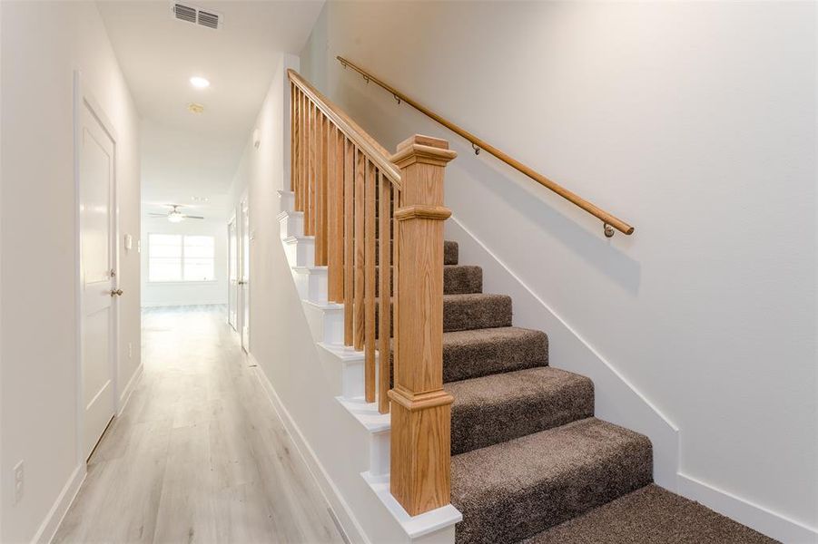 Staircase featuring ceiling fan and light hardwood / wood-style flooring