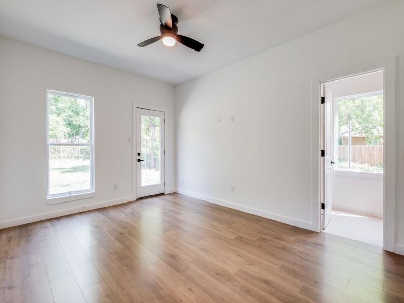 Empty room with light wood-type flooring, a healthy amount of sunlight, and ceiling fan