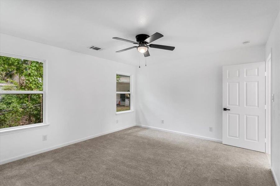 Unfurnished room featuring plenty of natural light, ceiling fan, and carpet floors