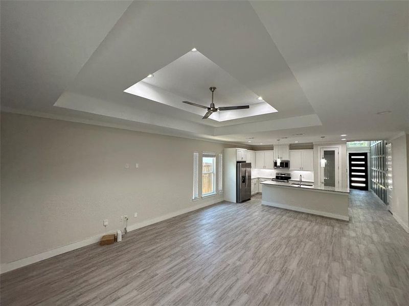 Living room featuring a tray ceiling, sink, ceiling fan, and light hardwood / wood-style tile flooring