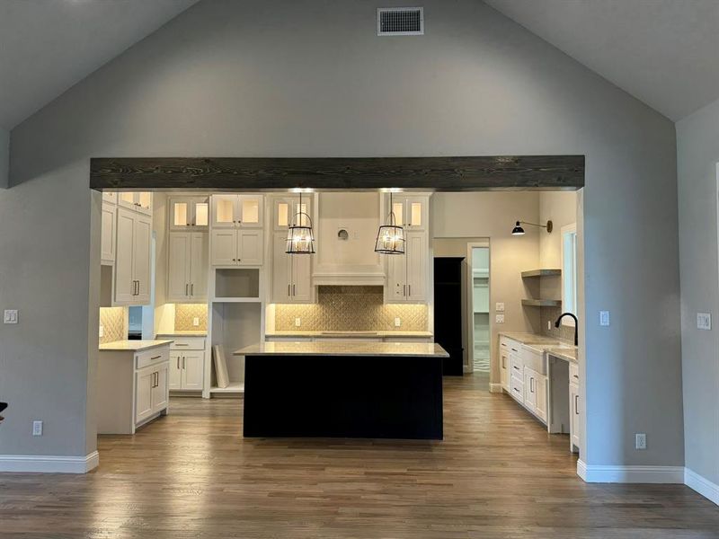 Kitchen featuring white cabinets, hanging light fixtures, and dark wood-type flooring