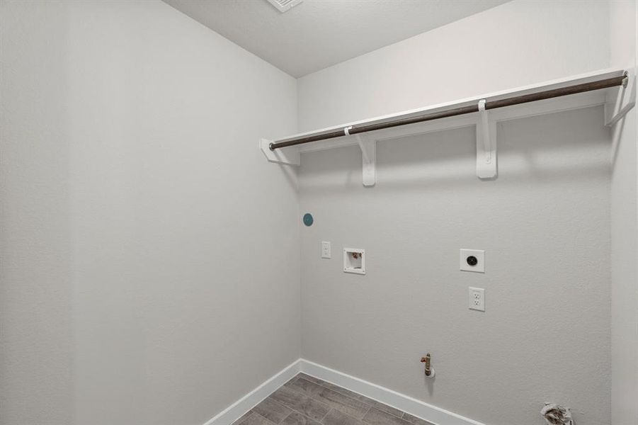 A perfect blend of functionality and comfort. Capture the essence of easy living with a first-floor laundry room, thoughtfully equipped with shelving for effortless organization. Both electric and gas connections available. Sample photo of completed home with similar floor plan. As built color and selections may vary.