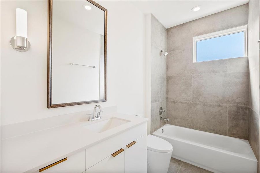 Full bathroom with tiled shower / bath, tile patterned floors, vanity, and toilet