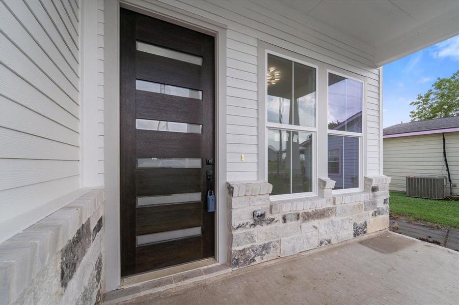 Lovely porch featuring a modern front door and elegant stone and hardie plank exterior.