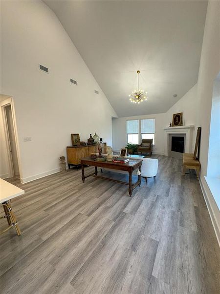 Living room featuring an inviting chandelier, lofted ceiling, and hardwood / wood-style floors