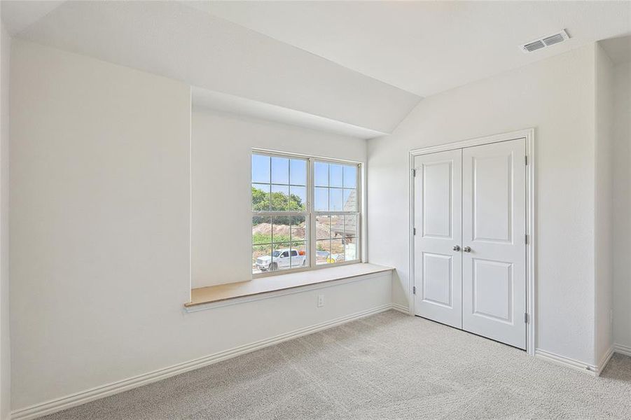 Unfurnished bedroom featuring a closet, light colored carpet, and vaulted ceiling